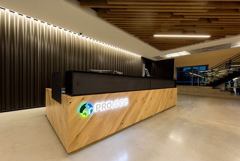 Front lobby area with custom-built wood desk and wall paneling integrated with LED lighting