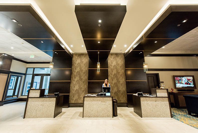 Hotel lobby with 3 front desks, decorative wood paneled walls and ceiling