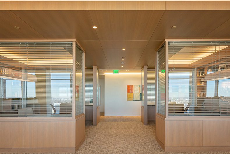 Spacious office space with glass cubicle partitions and wood ceiling system.