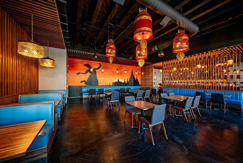 Restaurant dining area with booths and chair seating, colorful mural and wood paneled walls