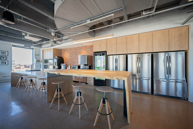 Office breakroom with bi-level table seating and kitchenette