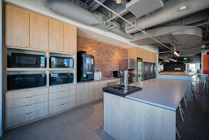 Office kitchen with wood cabinetry and installed kitchen island