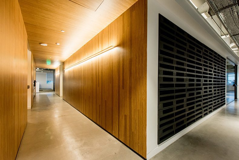 Office hallway with wood wall panels, LED track lighting and wood wall art installation