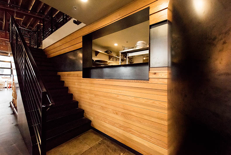 Black custom staircase against decorative wall with wood panels and metal integration