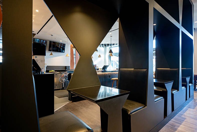 Restaurant booths with decorative wood dividers, glass table tops and upholstered seating