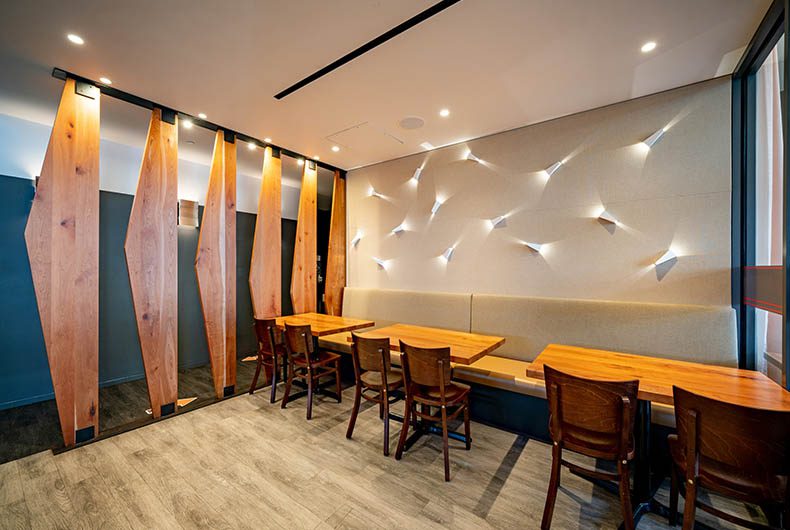 Restaurant dining area with banquette seating, wood table tops and decorative wood partitions