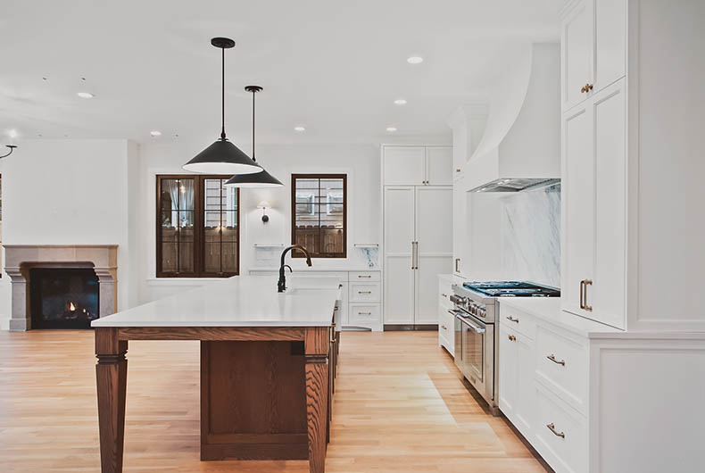 Home kitchen with wood island, white countertops and cabinetry